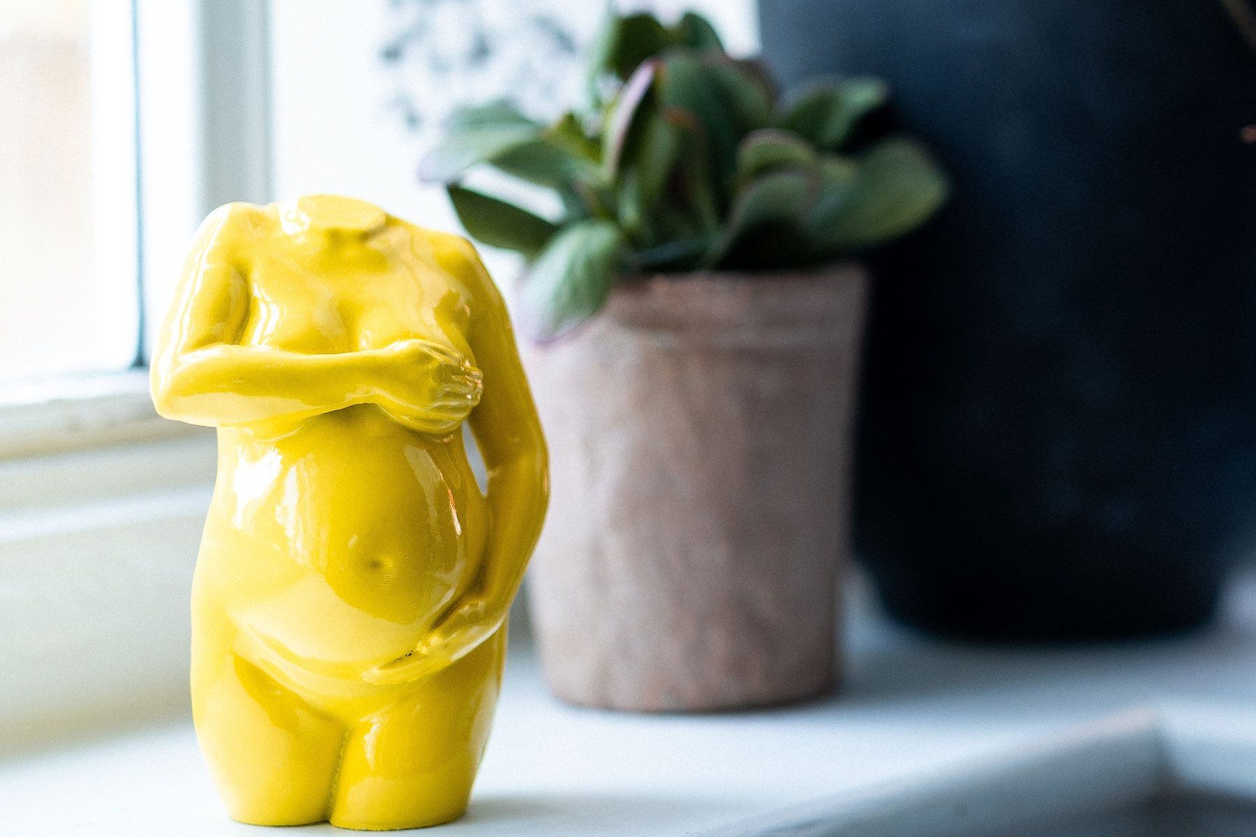 Yellow pregnancy sculpture on a bright windowsill